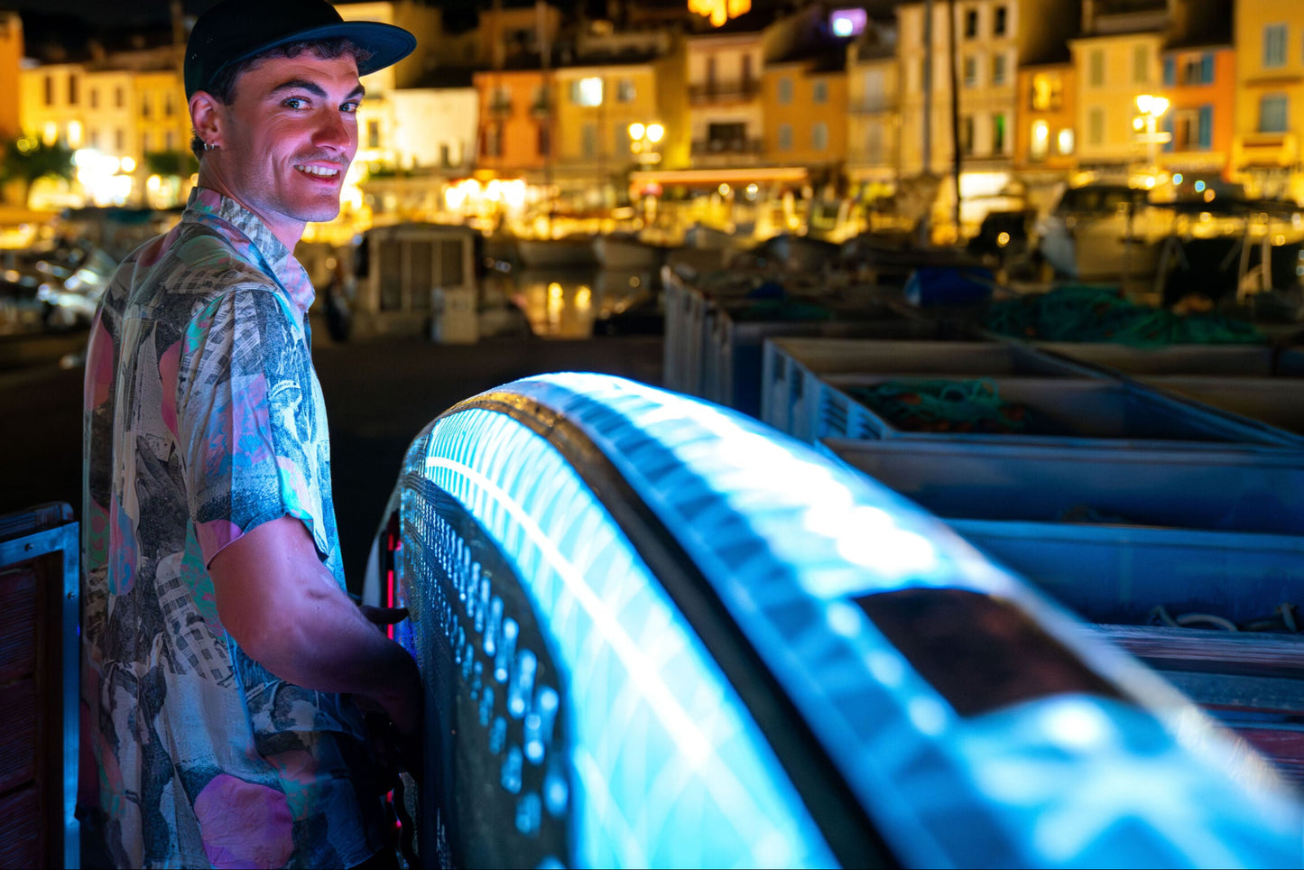 Man lit up at night next to an Inflatable LED Glow Paddleboard iSUP rental. Illuminates for nighttime, moonlight paddle parties on the water. Rent with delivery to docks, cabins, and vacation homes in the Flathead Valley, Montana. Book with MontanaBoarders.com.