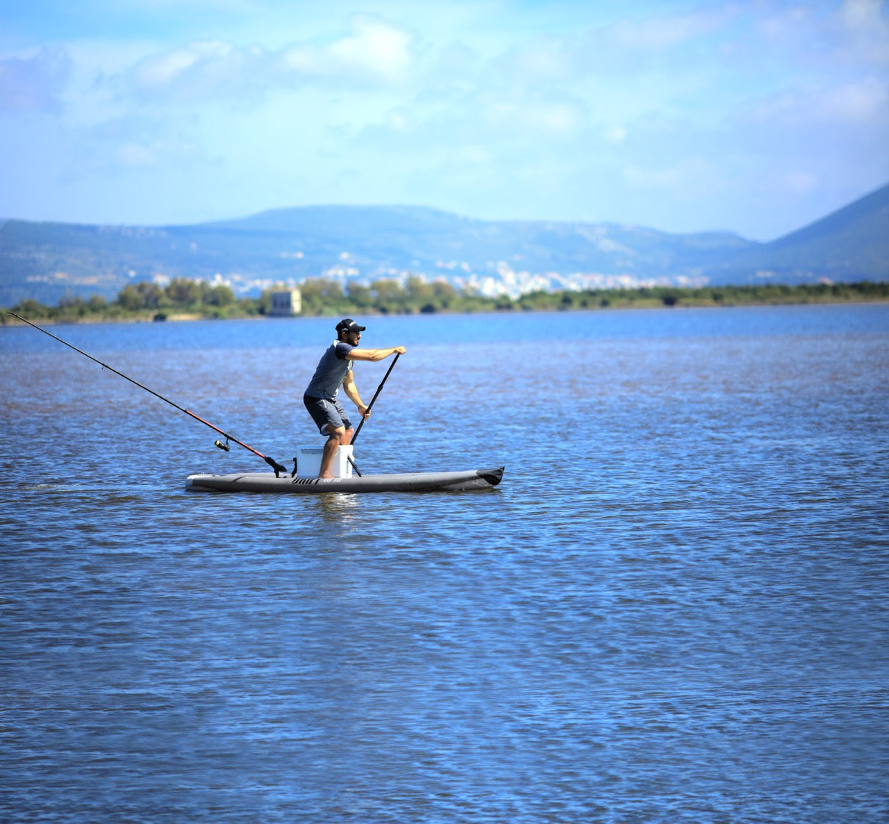 Fisherman paddling on inflatable paddleboard isup casting a line on Flathead Lake | Rent fishing gear from MTBoarders.com with delivery included. Or buy now from e-boarders.com