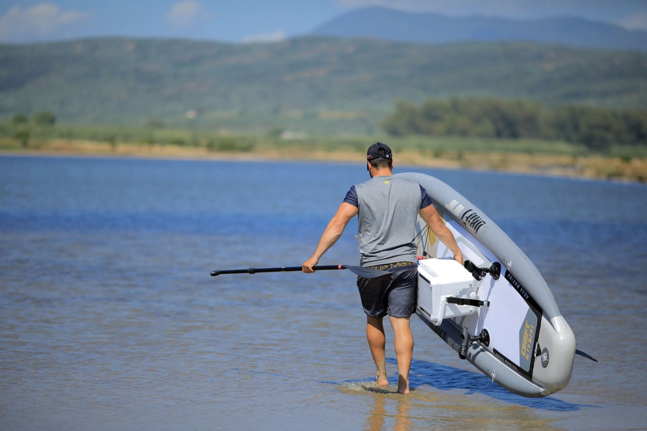 Fisherman walk with cooler attached to Drift iSUP inflatable paddleboard by Aqua Marina with fishing pole. Rent fishing gear from MTBoarders.com with delivery included. Or buy now from e-boarders.com