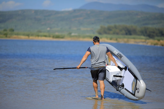 Fisherman walk with cooler attached to Drift iSUP inflatable paddleboard by Aqua Marina with fishing pole. Rent fishing gear from MTBoarders.com with delivery included. Or buy now from e-boarders.com