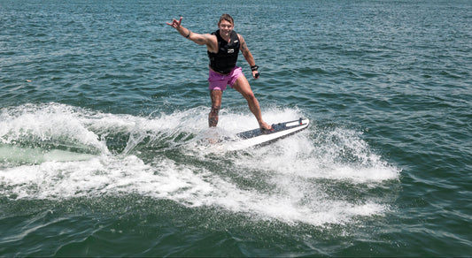 Young man gives hand signal on wake riding Awake RÄVIK electric wakeboard rental—carbon fiber high-speed ride for boat-free wakeboarding on Flathead Lake. Buy at E-Boarders.com. Rent with delivery, setup, training by MontanaBoarders.com and private lessons by MontanaBoardingSchool.com.