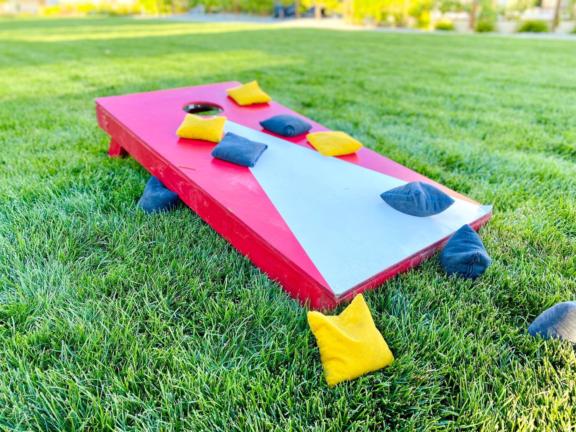 Cornhole board game rental set up on grass at Montana lake house by Montana Boarders. Pickup or have delivered across Flathead Valley and Whitefish.