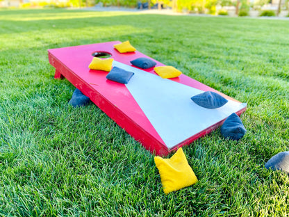 Cornhole board game rental set up on grass at Montana lake house by Montana Boarders. Pickup or have delivered across Flathead Valley and Whitefish.