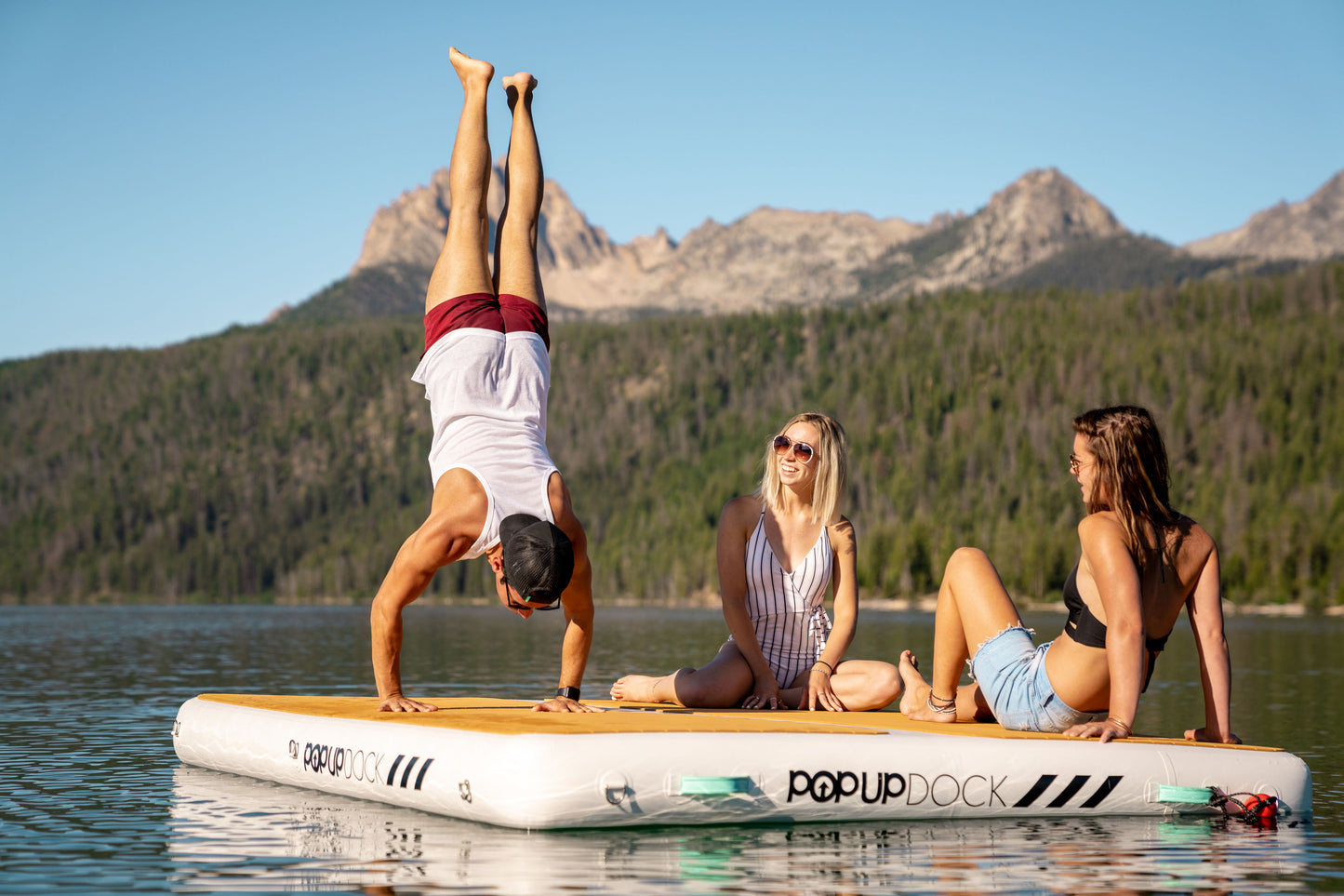 Handstand on Inflatable lake furniture bundle rental with floating dock, lounge chairs, and table—delivered to waterfront properties in Flathead Valley, Montana. Rent from MontanaBoarders.com purchase from flagship partner eboarders.com
