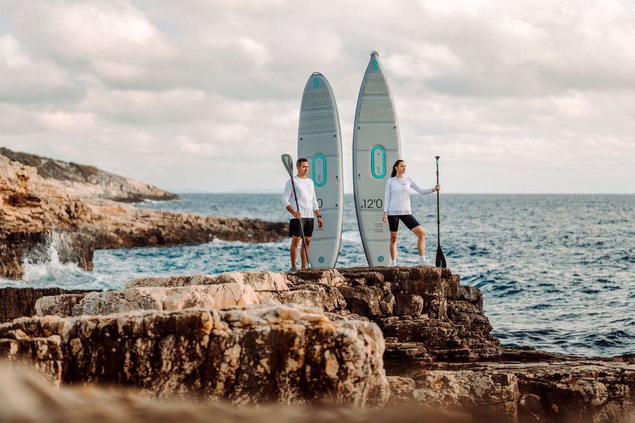 Two paddleboarders standing on rocks with SipaBoards self-inflating electric paddleboard rentals delivered to Flathead Valley lakefronts.